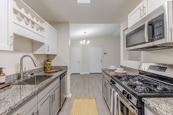 Kitchen with wood-designed flooring, stainless-steel appliances, and white cabinets.